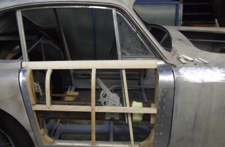 Bare Aceca body structure showing welded steel tubing and ash timber framing beneath hand-formed aluminium panels