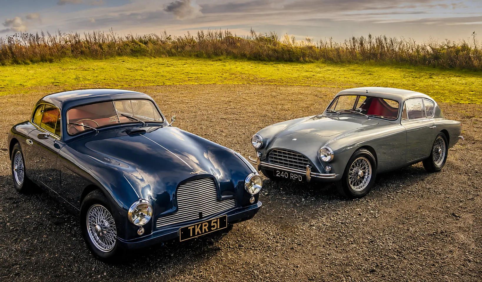 An AC Aceca and an Aston Martin DB2/4 parked side by side, showing the contrasting front grilles and proportions