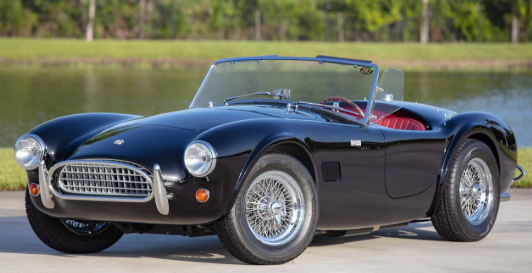 Black AC Cobra roadster with wire wheels, three-quarter front view