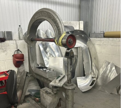 English wheeling machine and hand-shaped aluminium Aceca body panels in a coachbuilder's workshop