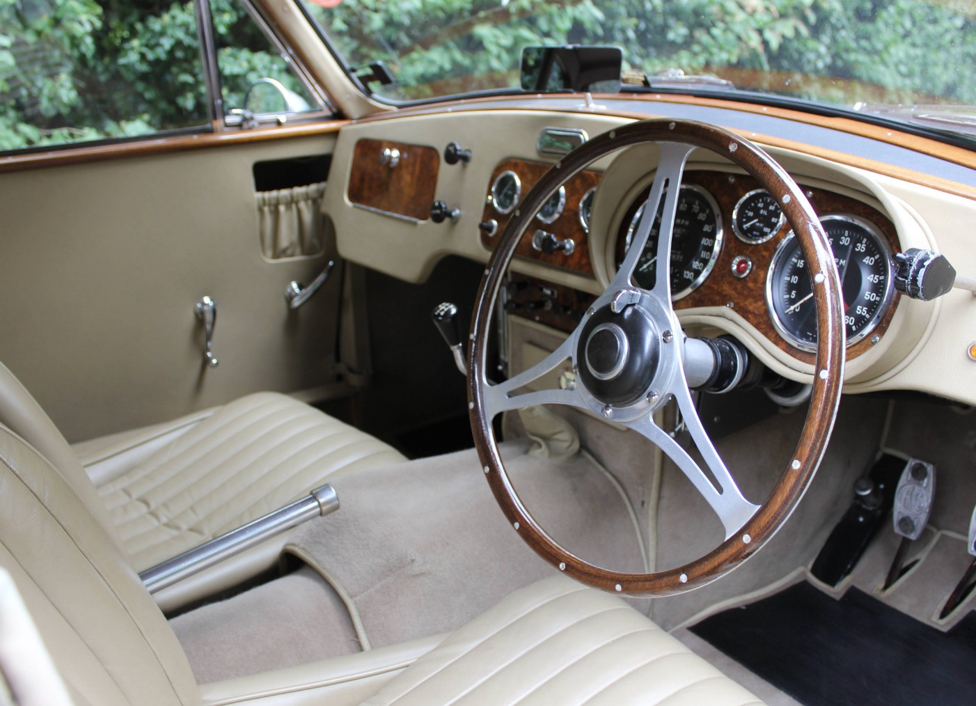 Cockpit interior of UBR 135 showing beige leather seats, wood-rimmed steering wheel and Smiths 130 mph speedometer
