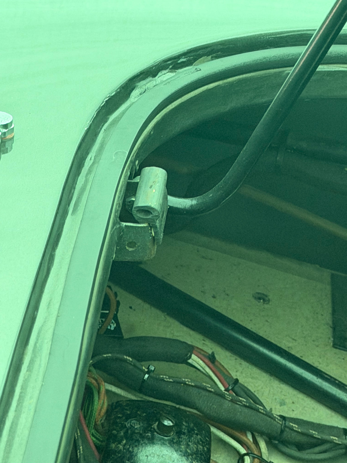 Close-up of an AC Aceca bonnet prop rod seated in its tubular socket on a small steel bracket at the edge of the engine bay.