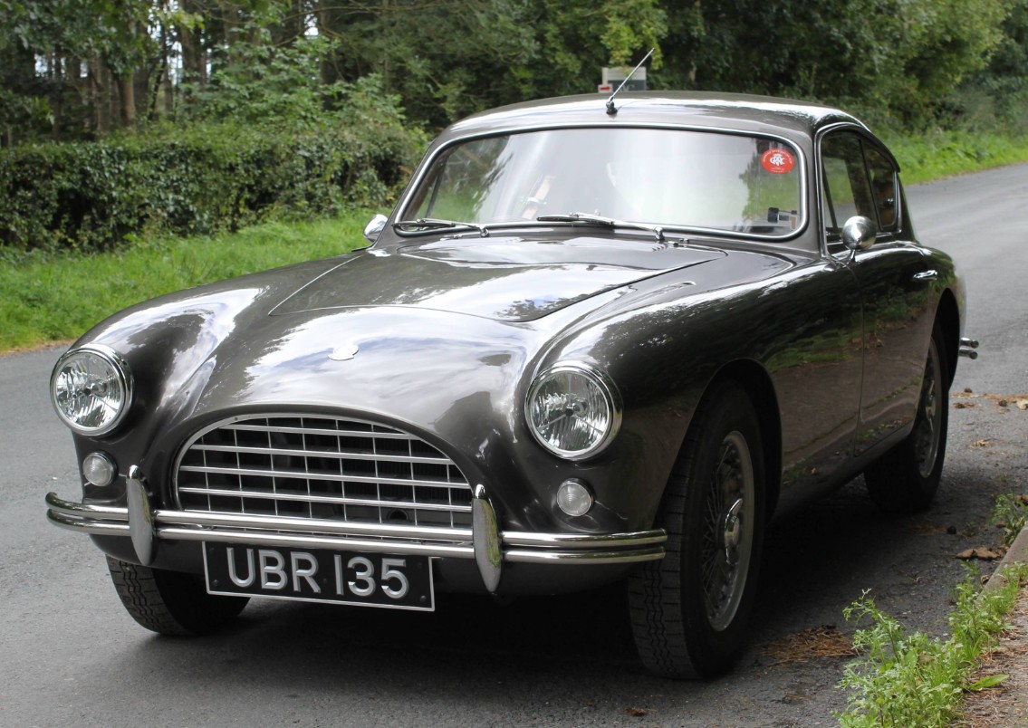 Front three-quarter view of 1958 AC Aceca-Bristol UBR 135 on a country lane, showing its hand-beaten aluminium fastback body and wire wheels