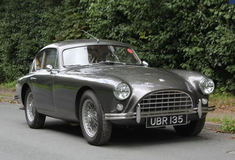 AC Aceca in silver-grey with wire wheels and registration UBR 135, photographed alongside an English country hedgerow